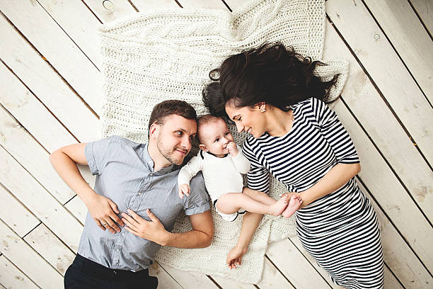 Young father, mother and cute baby lying on floor stock photo