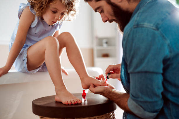 Young father painting small daughter's nails in a bathroom at home. A young father painting small daughter's nails in a bathroom at home. painting fingernails stock pictures, royalty-free photos & images