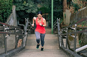 istock Young female athlete running up stairs 1301680726