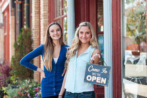 Young female business partners holding an open sign outside stock photo