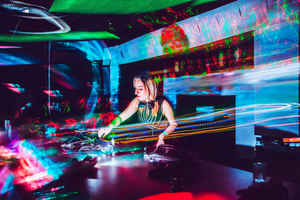 Young Female DJ Mixing Music in a Nightclub Young Female DJ Mixing Music in a Nightclub techno music stock pictures, royalty-free photos & images