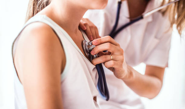 Young female doctor examining a small girl in her office. Unrecognizable young female doctor examining a small girl with stethoscope in her office. Close up. general practitioner stock pictures, royalty-free photos & images
