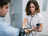 young female doctor measures the blood pressure of a male patient