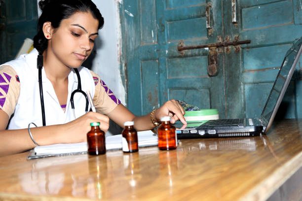 Young Female Doctor Working on Laptop Confident Young Female doctor working on Laptop & writing something in the book. developing countries stock pictures, royalty-free photos & images