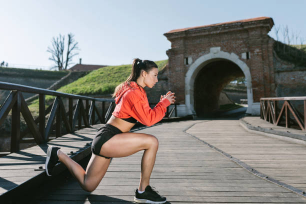 Young female doing squats outdoors on the bridge stock photo