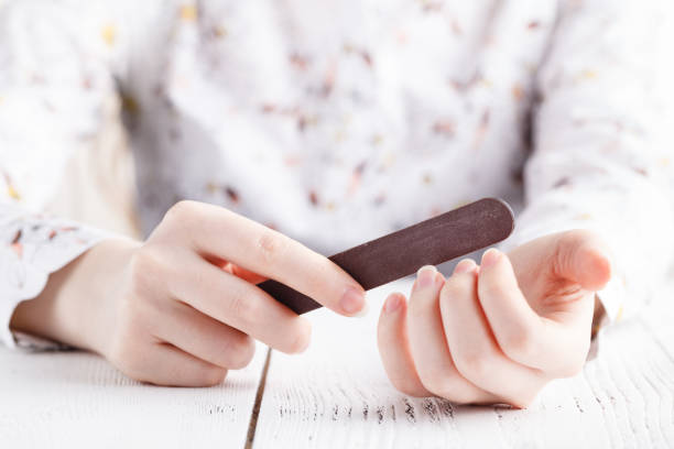 Young female filing nails Young female filing nails nail file stock pictures, royalty-free photos & images