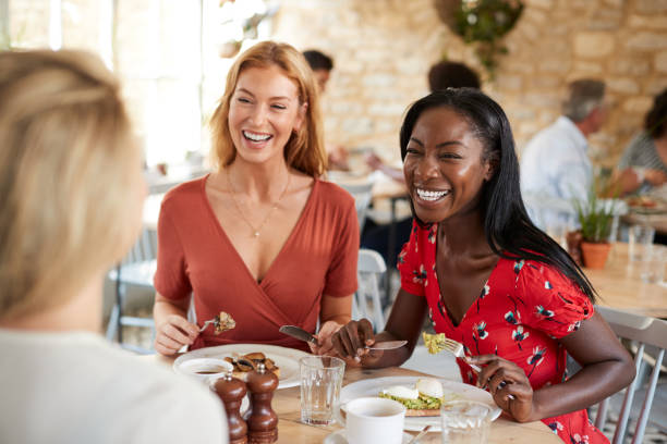 Young female friends smiling at brunch in a cafe, close up Young female friends smiling at brunch in a cafe, close up brunch stock pictures, royalty-free photos & images