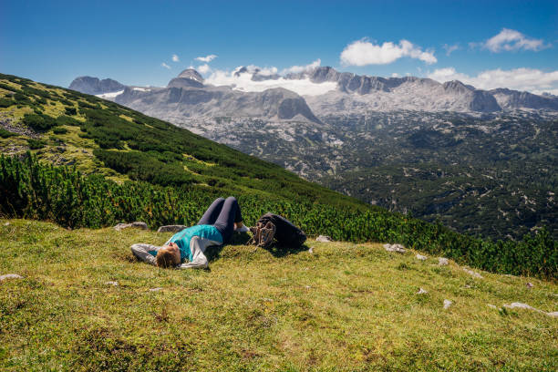Young female hiker lying on grassy slope Mountains and glacier on background dachstein mountains stock pictures, royalty-free photos & images