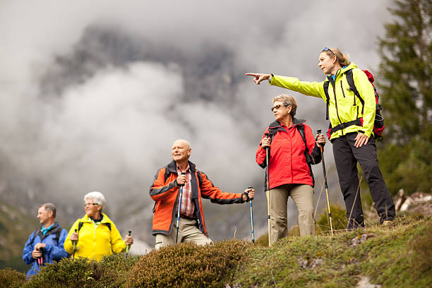 young female hiking guide showing senior group surrounding mount stock photo