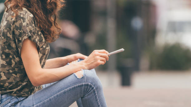 Young female holding a marijuana joint in her hand, ready to smoke. Urban weed smoking. stock photo