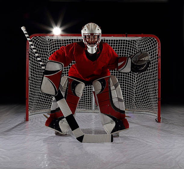 Young female ice hockey goalie. A young female ice hockey goalie guards the net. goalie stock pictures, royalty-free photos & images