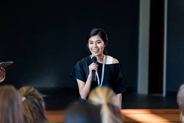Young female influencer speaks with crowd during seminar Young Hispanic woman gives a motivating speech during a conference or seminar. presentation speech stock pictures, royalty-free photos & images