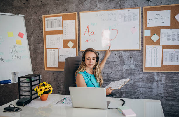 Young female professor holding online class for e-learning students One young female professor holding online class for e-learning students during coronavirus pandemic period. Online Tutor stock pictures, royalty-free photos & images