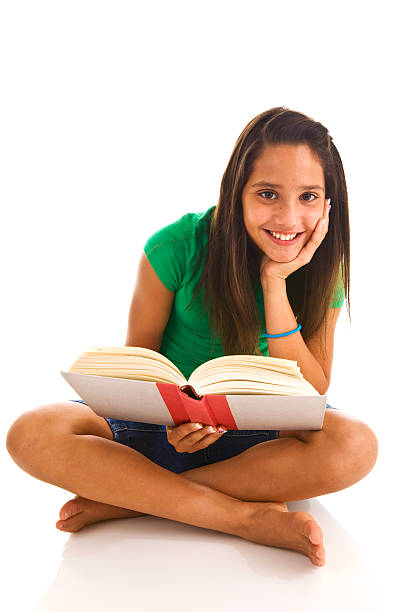 Young female teenager sitting cross legged reading a book stock photo