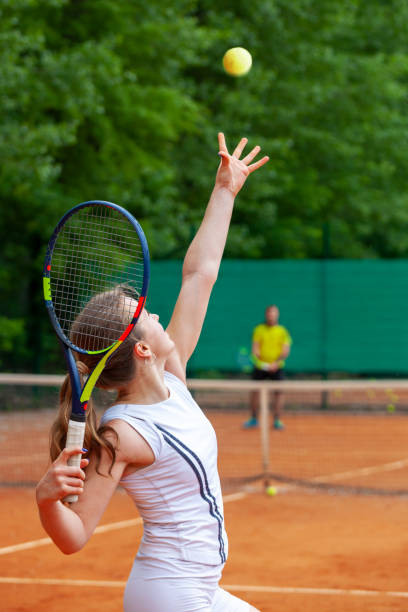 Young female tennis player serving. stock photo
