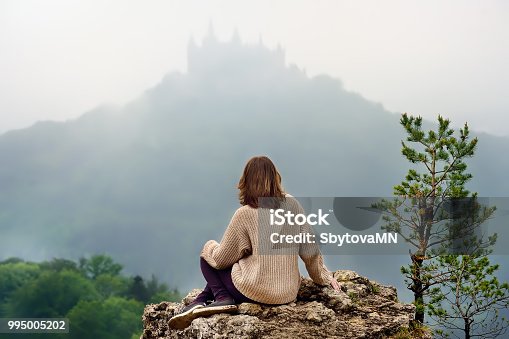 istock Young female tourist looking on famous Hohenzollern Castle in thick fog, Germany 995005202