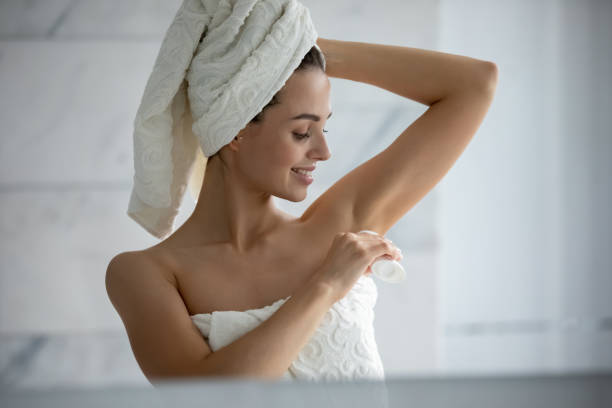 Young female using deodorant after shower in bathroom Millennial female wrapped in towel after shower use antiperspirant or deodorant after bath at home, young woman take care of armpit skin do daily beauty treatment in bathroom, hygiene concept deodorant stock pictures, royalty-free photos & images