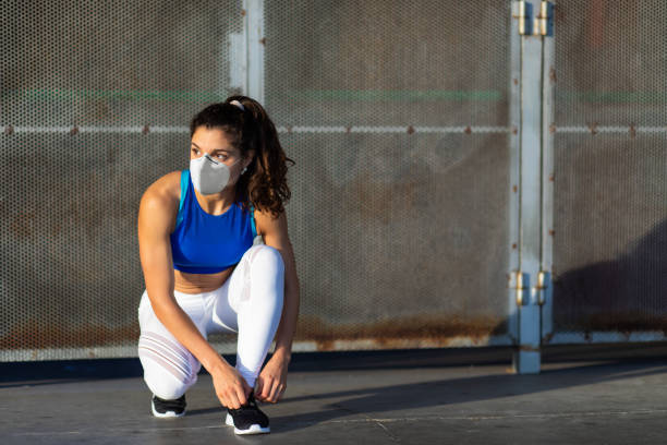 年輕適合的女運動員準備在冠狀病毒大流行危機下跑步 - n95 mask 個照片及圖片檔