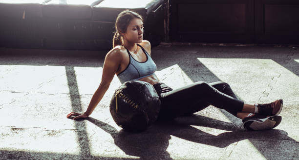 Young fit woman exercising with heavy ball at gym stock photo
