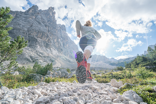 Sportive young woman exercising trail running on mountain trail in Alto Adige, Italy. People body conscious and heathy lifestyle concept.