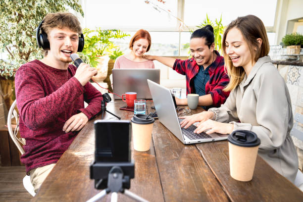 Young friends sharing content on streaming platform with digital web cam - Modern tech life concept with next gen people having fun vlogging live feeds interview on air social media networks stock photo