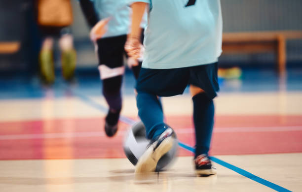 young futsal players and soccer ball with motion blur. indoor futsal soccer players in motion playing training game. indoor soccer sports hall. sport players kicking match. futsal training dribble - futsal imagens e fotografias de stock