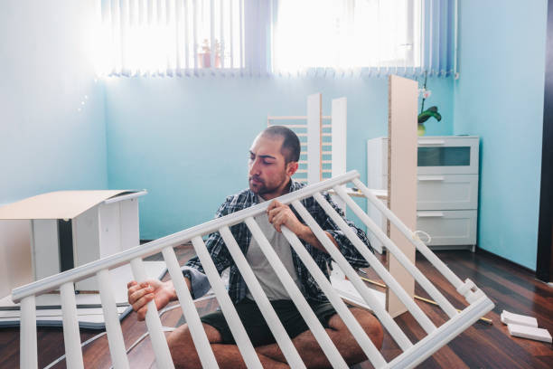 jonge toekomstige vader die een babywieg in zijn huis probeert samen te stellen - wiegman stockfoto's en -beelden