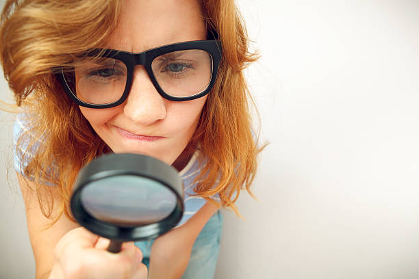 Young geek looking through magnifying glass. stock photo