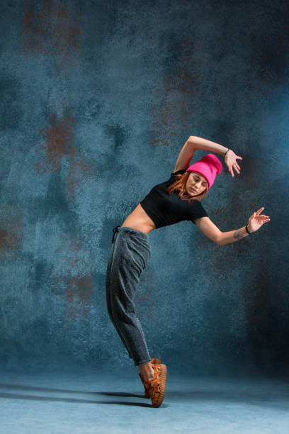 Young girl break dancing on blue studio background.