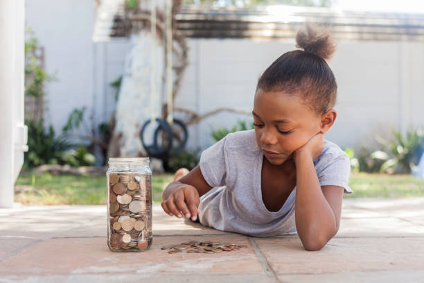 Young girl counting her saved coins. stock photo