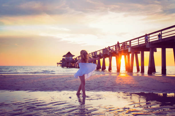 Young Girl Dancing on the Beach Color image of a young girl twirling happily on a beautiful beach in Naples, Florida during a sunset. naples florida beach photos stock pictures, royalty-free photos & images