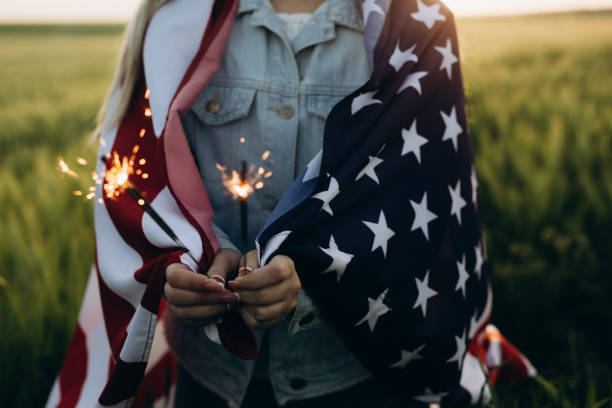 Young girl holding bengal fire with American flag at sunset. America celebrate 4th of July. Independence Day. Young girl holding bengal fire with American flag at sunset. America celebrate 4th of July. Independence Day july stock pictures, royalty-free photos & images