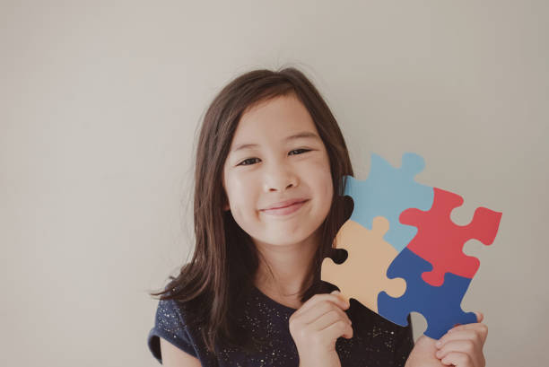 Young girl holding puzzle jigsaw,  child mental health concept, world autism awareness day, autism spectrum disorder awareness concept stock photo