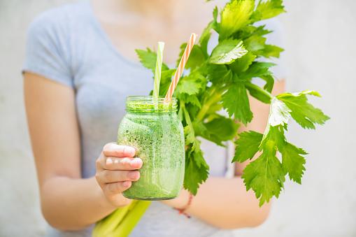 This image has an empty alt attribute; its file name is young-girl-holds-a-jar-of-green-smoothie-and-fresh-celery-in-her-picture-id1203834118