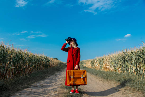 Young girl in coat with suitcase and binoculars stock photo