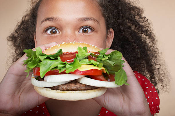 jeune fille à l'intérieur de manger un hamburger - eating burger photos et images de collection