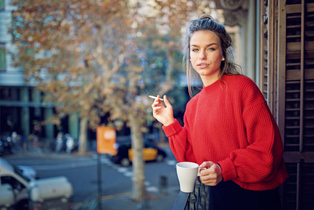 Young girl is smoking cigarette and drinking coffee at the balcony in the morning  little girl smoking cigarette stock pictures, royalty-free photos & images