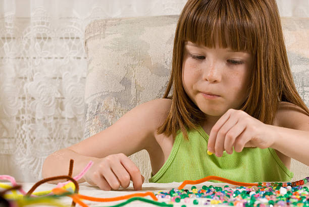 Young girl making bead bracelets stock photo