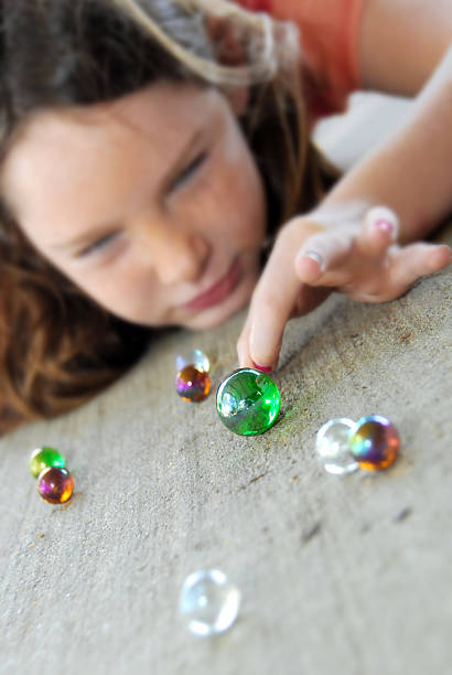 Young girl playing marbles stock photo