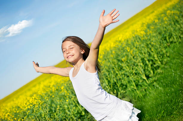 A young girl running through a field with her arms open little girl standing in front of canola swedish girl stock pictures, royalty-free photos & images