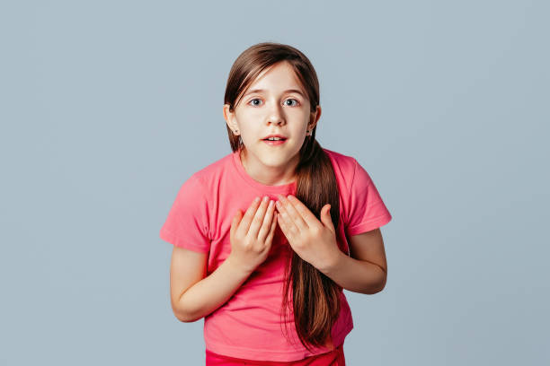 young girl sees something curious and gasping amazed surprised by unexpected news, presses hands on chest, open mouth. isolated on gray background - omg girl bildbanksfoton och bilder