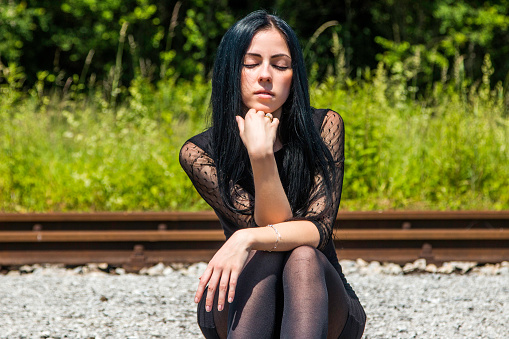Girl sitting on disused train tracks in countryside 