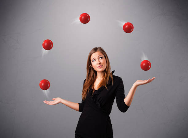 young girl standing and juggling with red balls stock photo