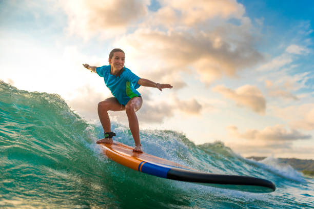 young girl surfing at sunset - surf imagens e fotografias de stock