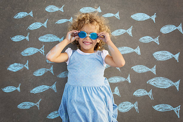 Young girl underwater imagination Little girl lying on her back on the street, surrounded by the drawing of fishes pisces stock pictures, royalty-free photos & images