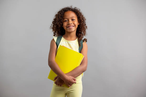 Young Girl Wearing Backpack And Holding A Notebook stock photo