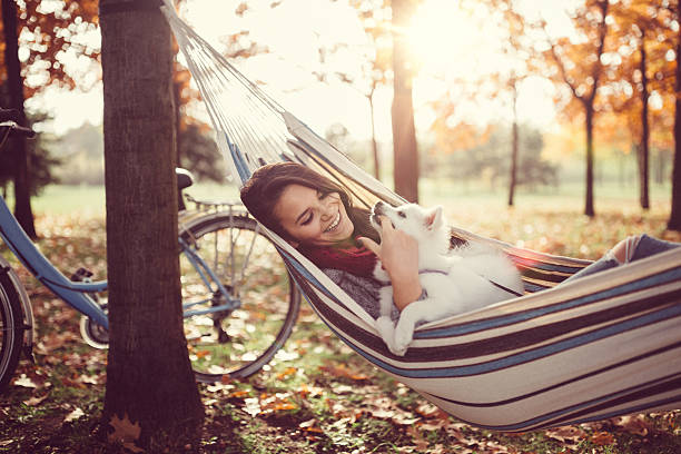 Young girl with cute dog in hammock Woman with doggy relaxing in the autumn park beautiful young brunette girl playing with her dog stock pictures, royalty-free photos & images