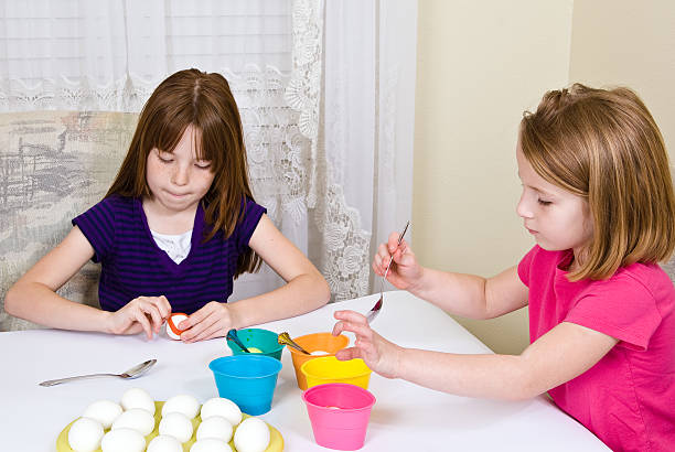 Young girls coloring Easter Eggs stock photo