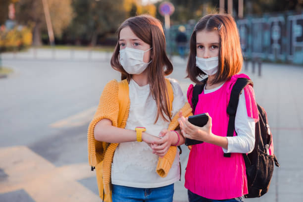 jeunes filles avec des masques de protection se promenant à l’extérieur - smartphone car photos et images de collection