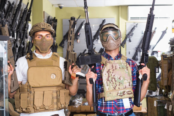 Young guys in military equipment with rifle in airsoft shop Young positive russian guys in military equipment with rifle in airsoft shop militia stock pictures, royalty-free photos & images